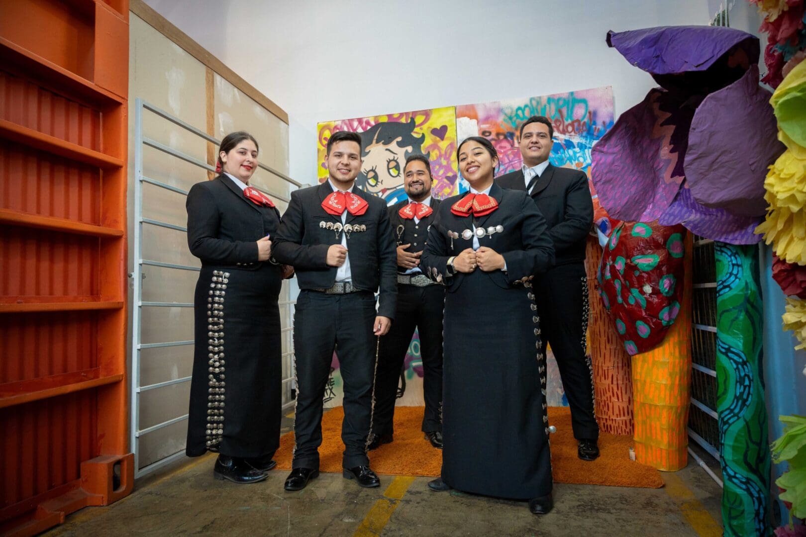 Mariachi band posing in colorful room.