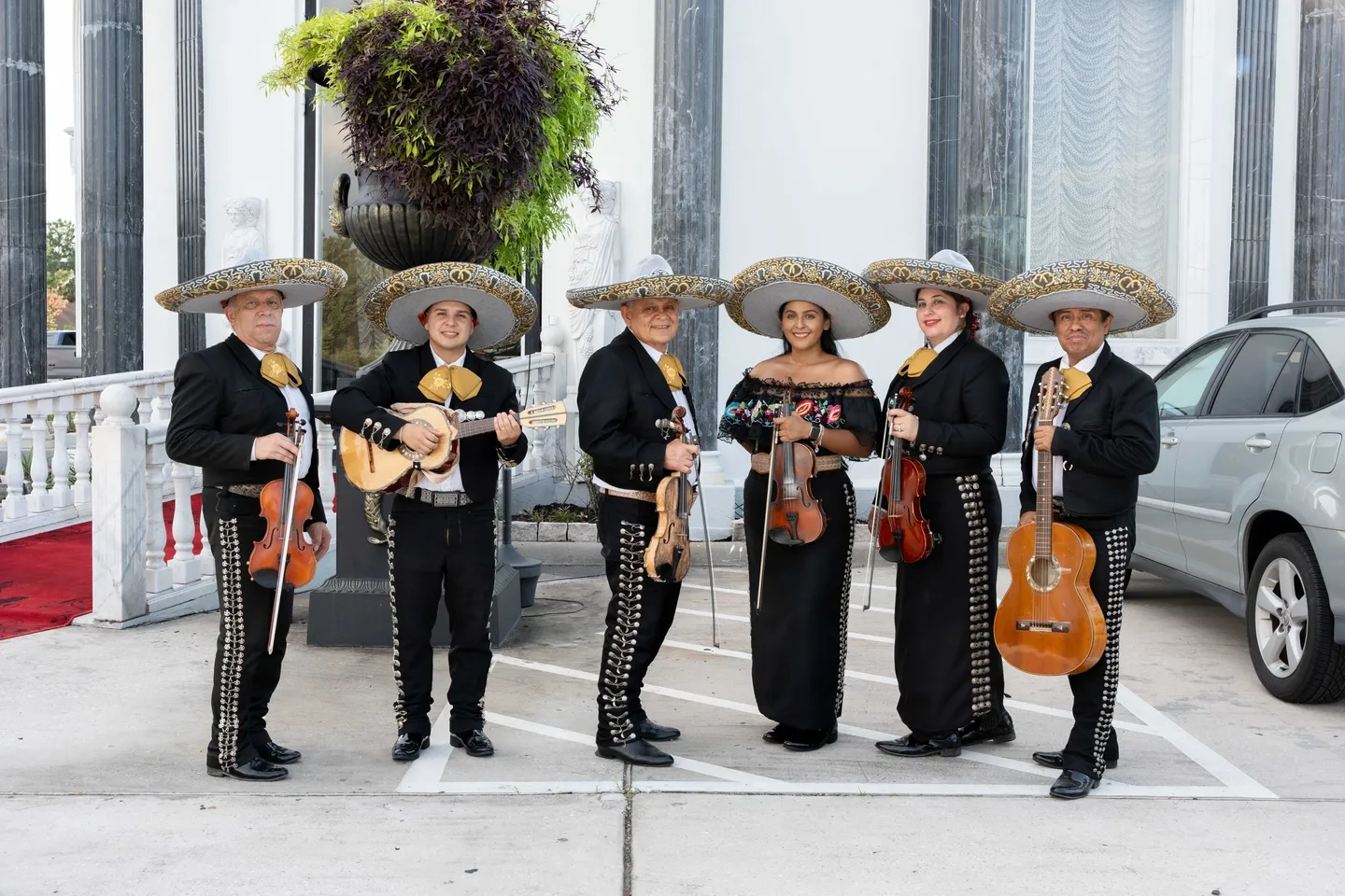 Mariachi band posing with instruments outdoors.