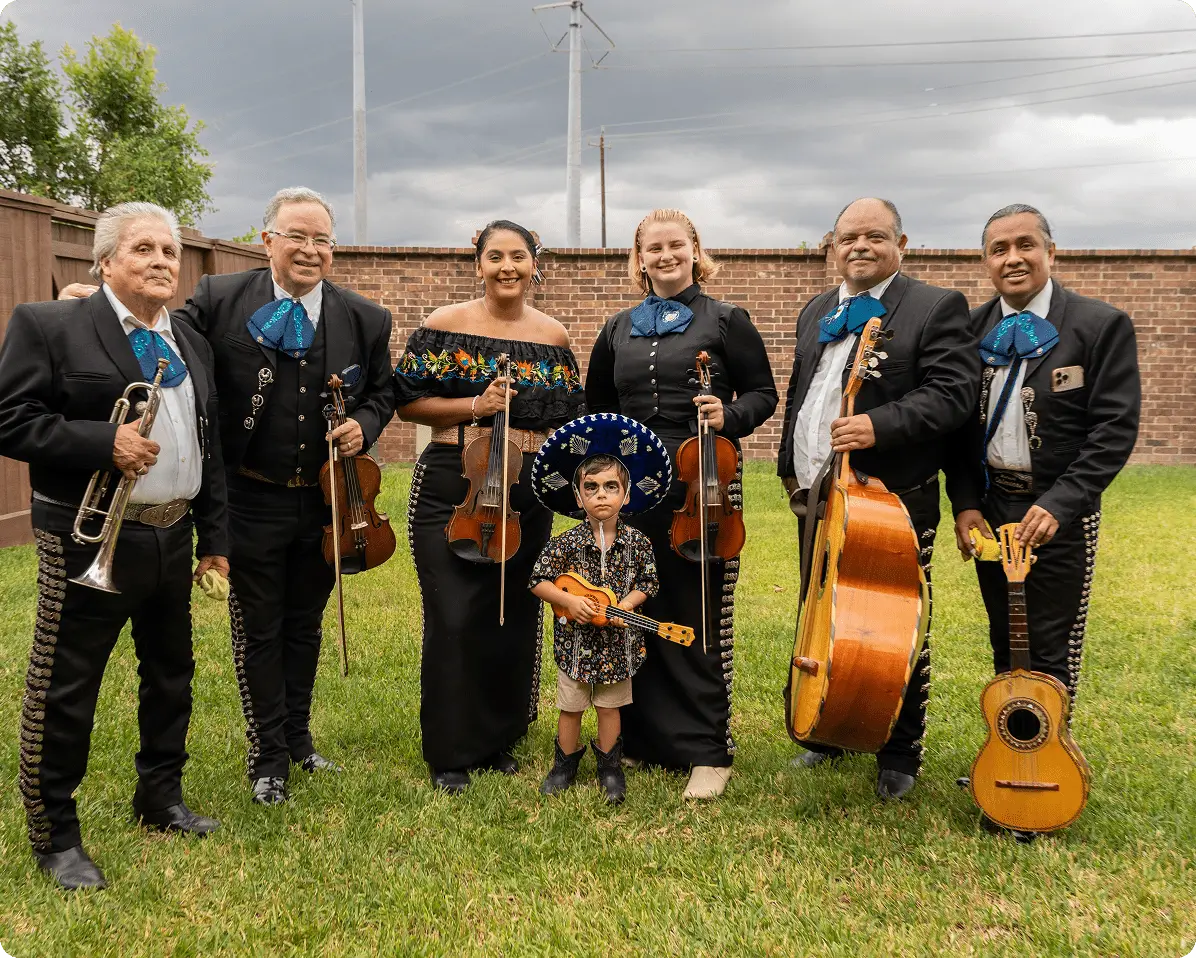 Mariachi band with instruments standing outdoors.
