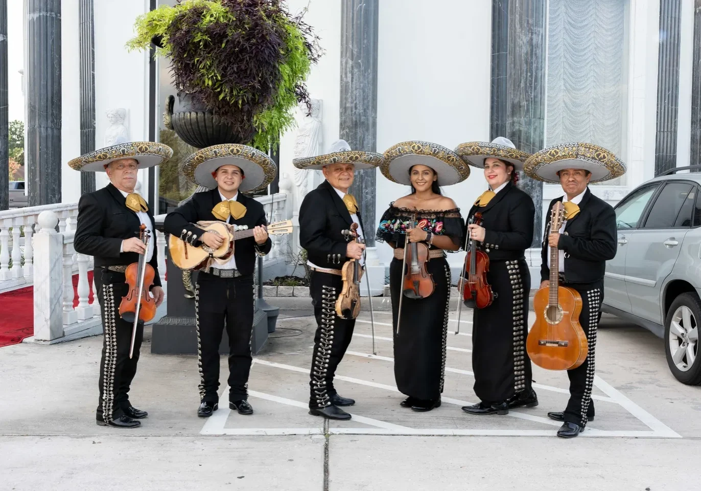 Mariachi band posing with instruments outdoors.